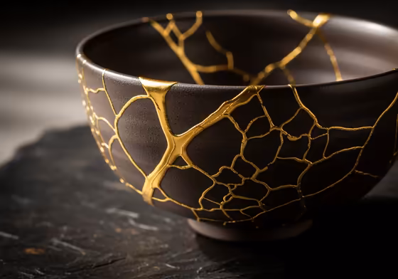 A beautifully repaired kintsugi bowl, with cracks filled with shimmering gold, symbolizing strength and beauty in brokenness.