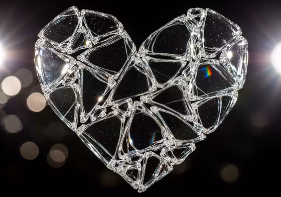 An artistic representation of a heart made of shattered glass, with light refracting through the pieces, symbolizing heartbreak.